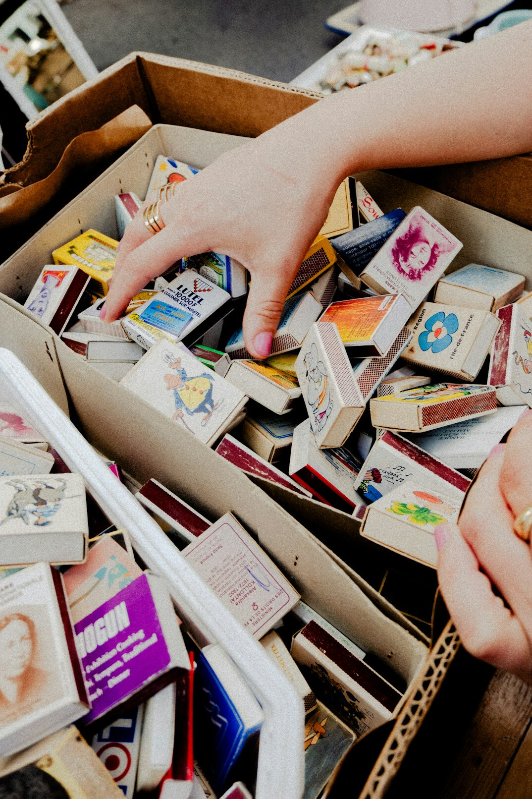 Hands sorting through a large archive of vintage advertising posters and print materials